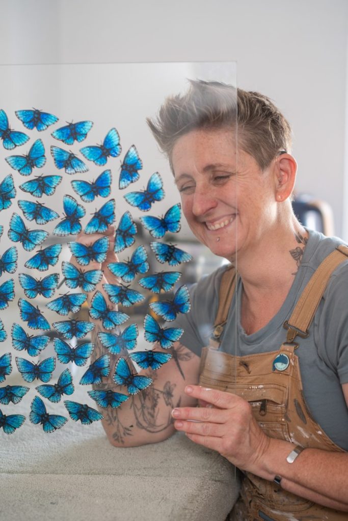 Danni Bradford painting blue butterflies onto glass.
Photo: Jim Wileman